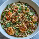 Colorful Asian Noodle Bowl topped with tender shrimp, julienned carrots, zucchini, and fragrant cilantro, perfect for a quick weeknight dinner.