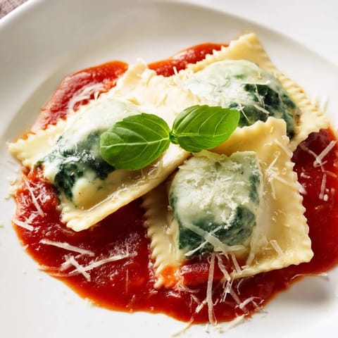 Tender ravioli filled with creamy ricotta and spinach, swimming in rich tomato sauce with a garlic aroma.  