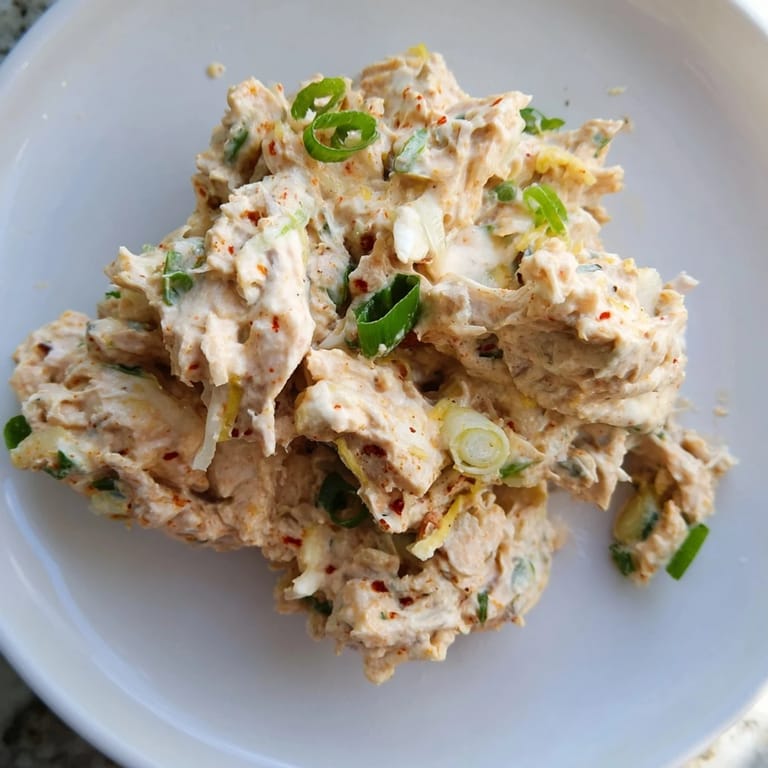 Vibrant spicy zesty tuna salad with creamy dressing and lemon wedges, highlighting fresh ingredients for easy American-style meal prep.