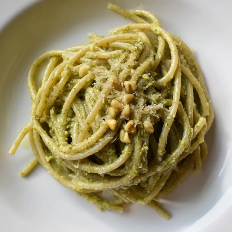 Steaming bowl of creamy sunflower seed pesto pasta served with a lemon wedge.  