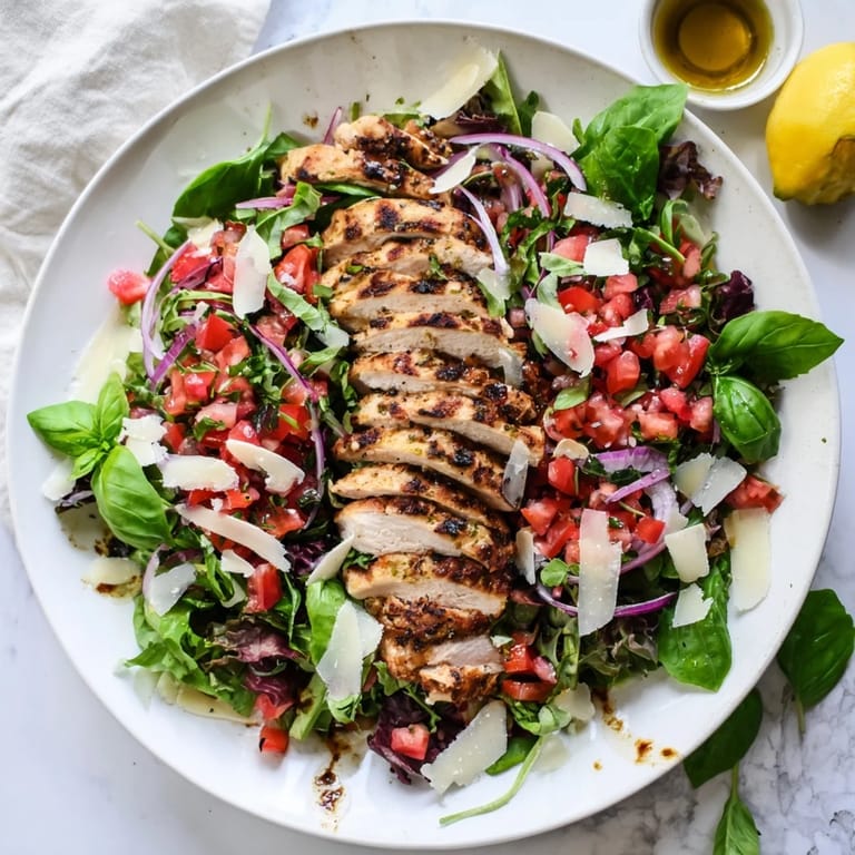Plated Bruschetta Chicken Salad features juicy grilled chicken breasts over crisp romaine and arugula, crowned with a zesty tomato and fresh basil topping, ready for a light Italian-American lunch.  
