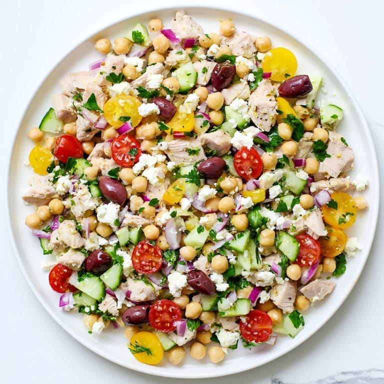 Savory Mediterranean Chickpea Chicken Salad featuring tender chicken, creamy feta, Kalamata olives, and fresh vegetables on a bright white platter.