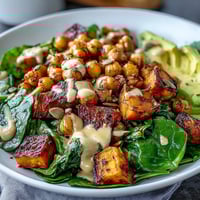 Roasted sweet potato and chickpea bowl topped with creamy avocado and fresh cilantro.