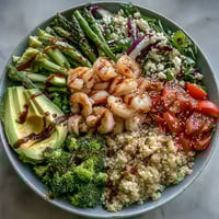 A vibrant Rainbow Vegetable Detox Bowl with colorful veggies, juicy shrimp, creamy avocado, and fluffy quinoa drizzled with balsamic dressing.
